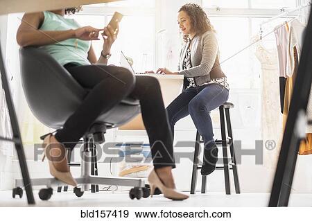 View underneath desk of businesswomen working in office View Large Photo Image Stock Photo - View underneath desk of businesswomen working in office. Fotosearch