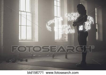 Stock Image - Virtual words circling Black athlete checking fitness tracker. Fotosearch
