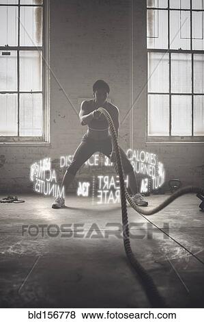 Stock Photo - Virtual words circling Black athlete working out with ropes. Fotosearch