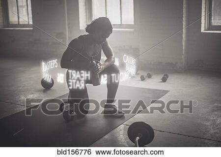 Stock Photograph - Virtual words circling Black athlete checking fitness tracker. Fotosearch