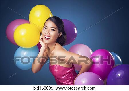 Stock Photography - Woman smiling with party balloons. Fotosearch