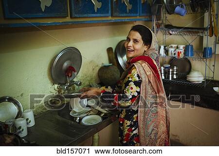 Stock Image - Woman washing dishes in kitchen. Fotosearch