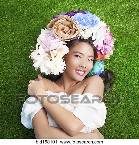 Stock Image - Woman wearing flower crown on artificial grass. Fotosearch