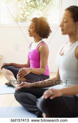 Stock Image - Women meditating in yoga class. Fotosearch