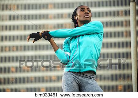Stock Image - Black runner stretching near highrise building. Fotosearch
