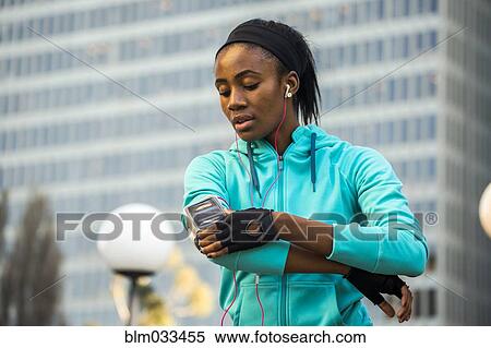Black runner using cell phone near high rise buildings View Large Photo Image Stock Photography - Black runner using cell phone near high rise buildings. Fotosearch