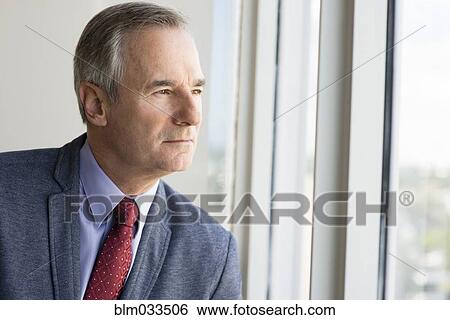 Caucasian businessman looking out office window View Large Photo Image Stock Photograph - Caucasian businessman looking out office window. Fotosearch