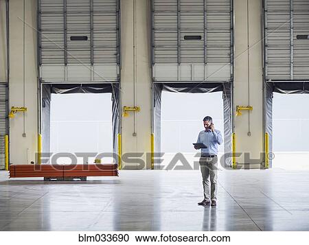 Caucasian businessman talking on cell phone in warehouse View Large Photo Image Stock Image - Caucasian businessman talking on cell phone in warehouse. Fotosearch