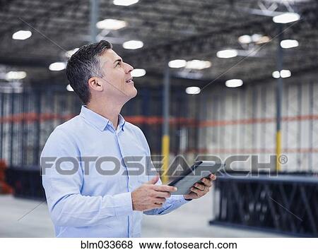 Caucasian businessman using digital tablet in empty warehouse View Large Photo Image Stock Photo - Caucasian businessman using digital tablet in empty warehouse. Fotosearch