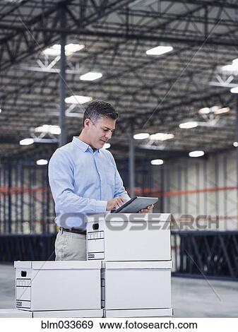 Stock Photo - Caucasian businessman using digital tablet in empty warehouse. Fotosearch