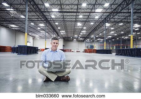 Caucasian businessman using laptop in empty warehouse View Large Photo Image Stock Image - Caucasian businessman using laptop in empty warehouse. Fotosearch
