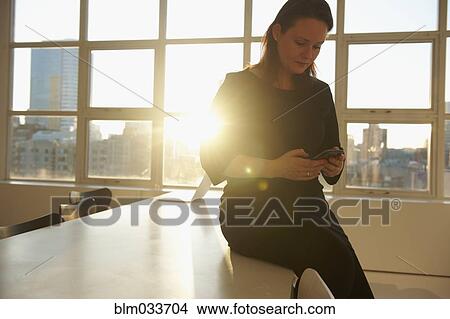 Picture - Caucasian businesswoman using cell phone in office. Fotosearch