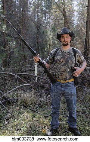 Caucasian hunter holding gun in forest View Large Photo Image Stock Photo - Caucasian hunter holding gun in forest. Fotosearch