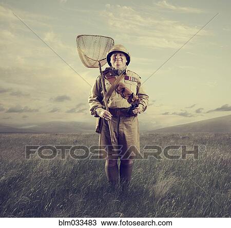 Stock Image - Caucasian hunter holding net in remote field. Fotosearch