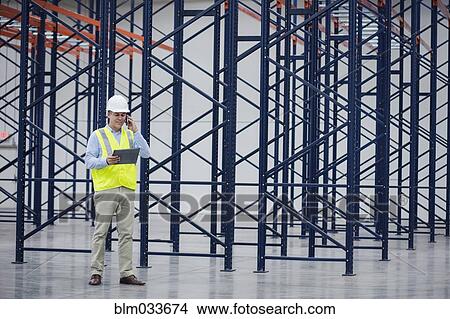 Picture - Caucasian worker using digital tablet in empty warehouse. Fotosearch