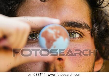 Picture - Close up of Hispanic man holding miniature globe. Fotosearch