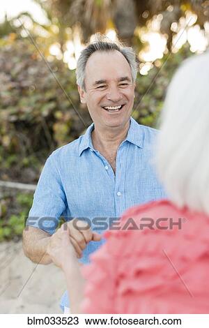 Stock Image - Close up of older Caucasian couple talking on beach. Fotosearch