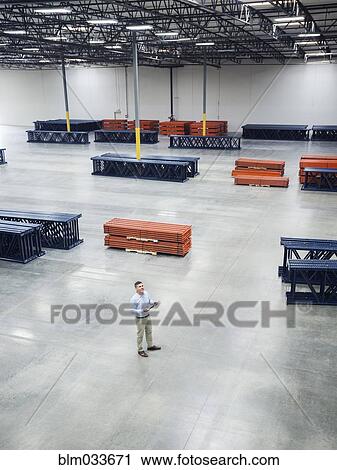 High angle view of Caucasian businessman standing in empty warehouse View Large Photo Image Stock Image - High angle view of Caucasian businessman standing in empty warehouse. Fotosearch