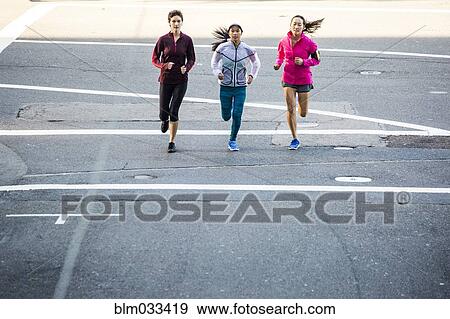 Stock Photo - High angle view of women running in city street. Fotosearch