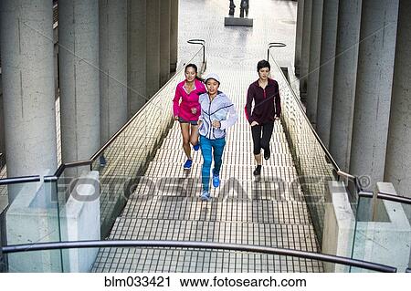 Stock Image - High angle view of women running on staircase. Fotosearch