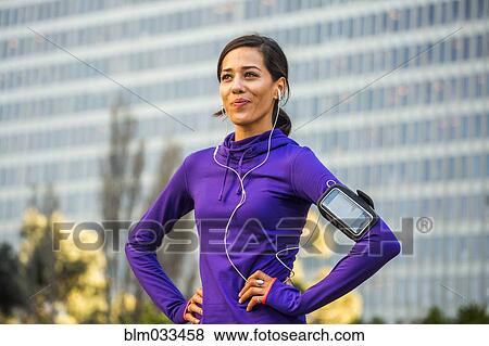 Stock Photo - Hispanic runner standing near high rise building. Fotosearch