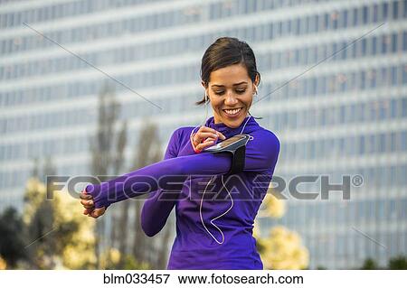Stock Photo - Hispanic runner using cell phone near high rise building. Fotosearch