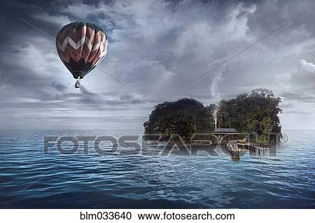 Stock Image - Hot air balloon floating over house on tropical island. Fotosearch