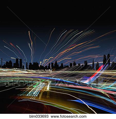 Stock Image - Light trails near New York City skyline at night, New York, United States. Fotosearch