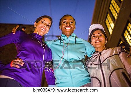 Stock Photo - Low angle view of runners smiling at night. Fotosearch