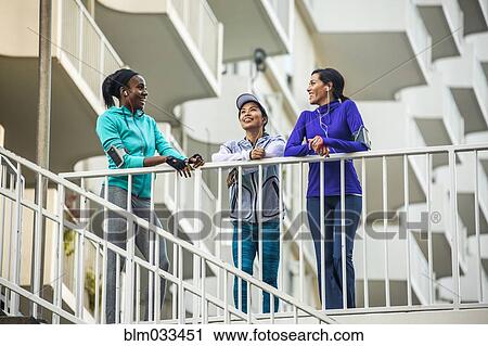 Stock Image - Low angle view of runners standing at railing. Fotosearch