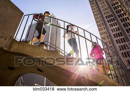 Stock Photo - Low angle view of women running on urban staircase. Fotosearch