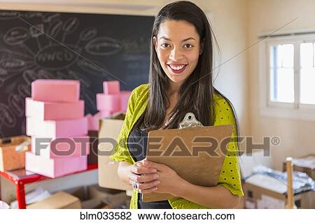 Mixed race businesswoman holding clipboard in office View Large Photo Image Stock Image - Mixed race businesswoman holding clipboard in office. Fotosearch
