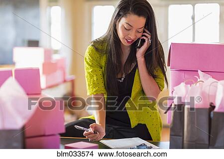 Picture - Mixed race businesswoman talking on telephone in office. Fotosearch