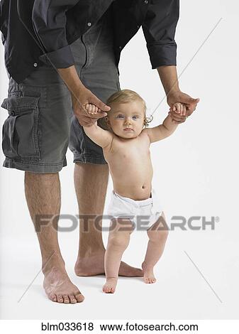 Stock Photo - Mixed race father helping baby girl learn to walk. Fotosearch