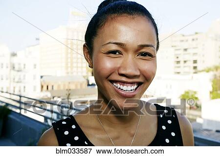 Stock Photo - Mixed race woman smiling on urban rooftop. Fotosearch