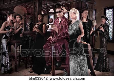 Stock Image - Models surrounding powerful man in pajamas at party. Fotosearch