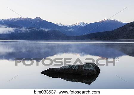 Mountains reflecting in still lake, Hokitika, South Westland, New Zealand View Large Photo Image Stock Photo - Mountains reflecting in still lake, Hokitika, South Westland, New Zealand. Fotosearch
