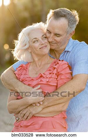 Stock Photo - Older Caucasian couple hugging on beach. Fotosearch