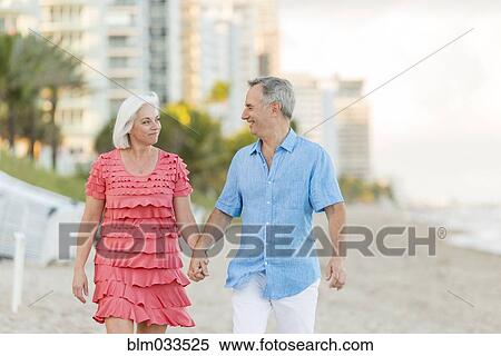 Stock Photography - Older Caucasian couple walking on beach. Fotosearch
