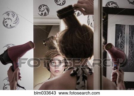 Stock Image - Overwhelmed Caucasian woman styling her hair. Fotosearch