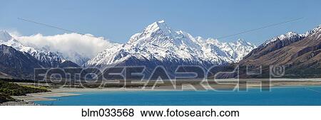 Stock Photo - Panoramic view of snowcapped mountains over remote lake, Mount Cook Village, Mckenzie Country, New Zealand. Fotosearch