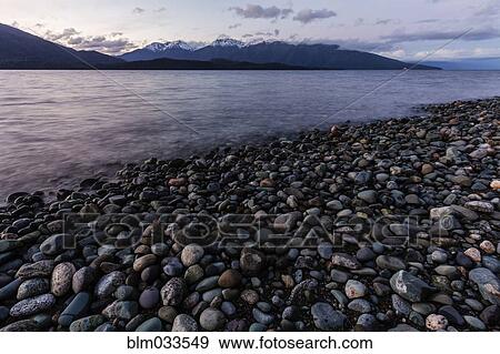 Stock Photo - Rocks near remote riverbed under mountains, Te Anau, Southland, New Zealand. Fotosearch