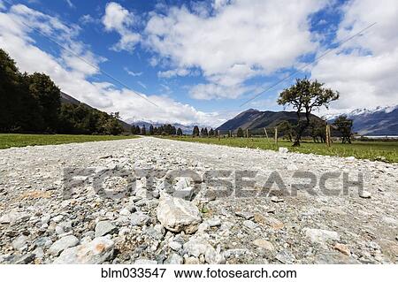 Stock Photo - Rocky road through remote fields and mountains. Fotosearch