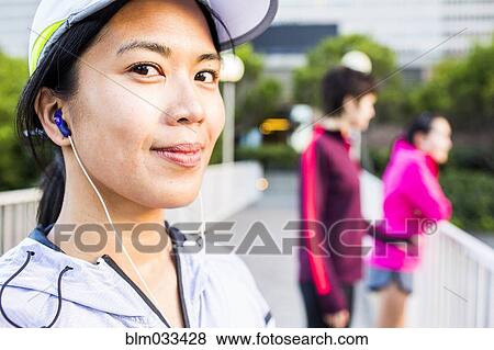Stock Photo - Runner listening to earbud in city. Fotosearch