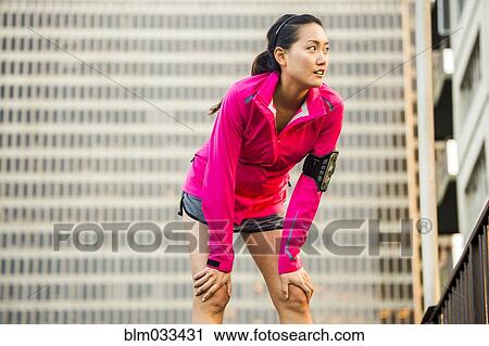 Stock Image - Runner resting near highrise building. Fotosearch