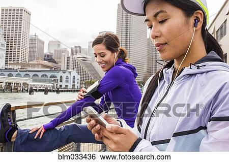 Stock Photograph - Runner using cell phone at waterfront, San Francisco, California, United States. Fotosearch