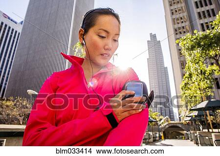 Picture - Runner using cell phone in city. Fotosearch