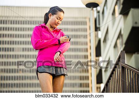 Stock Image - Runner using cell phone near highrise building. Fotosearch