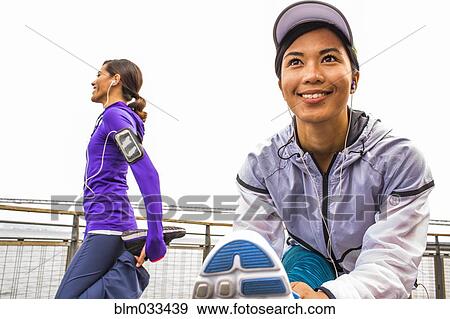 Stock Photo - Runners stretching at waterfront. Fotosearch