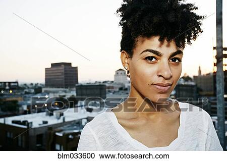 Serious woman standing on urban rooftop View Large Photo Image Stock Image - Serious woman standing on urban rooftop. Fotosearch